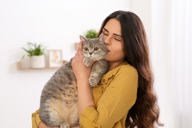 Photo of Young woman kissing her adorable cat at home