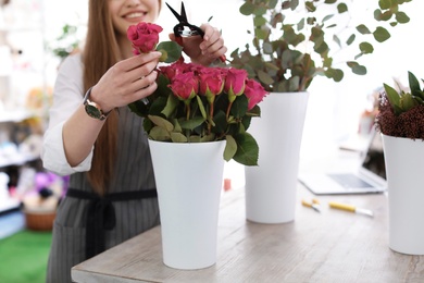 Female florist making beautiful bouquet in flower shop, closeup