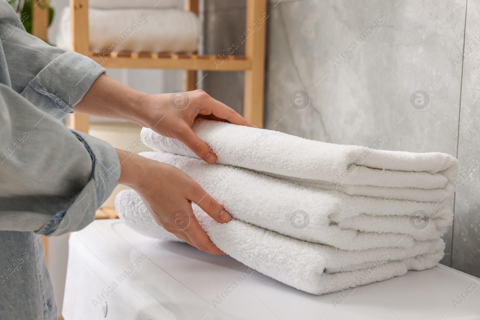 Photo of Woman with stack of clean towels indoors, closeup