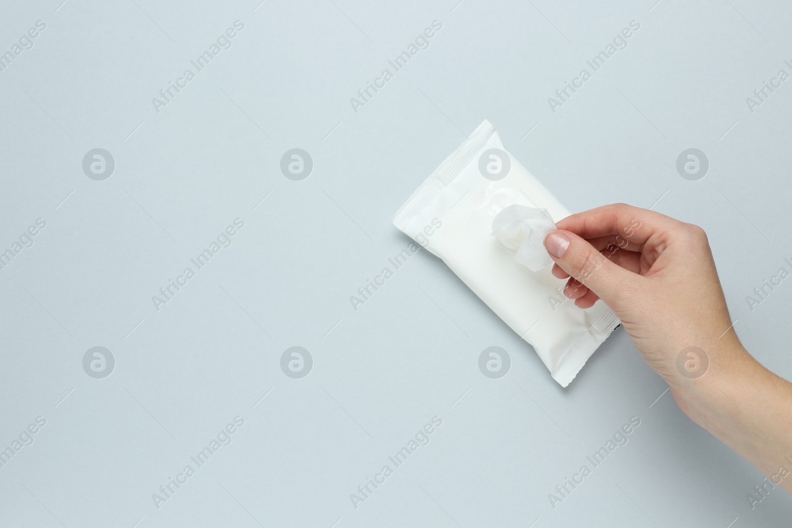 Photo of Woman taking wet wipe from pack on light background, top view. Space for text