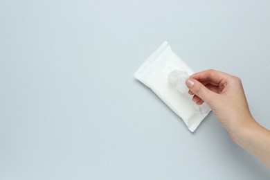 Photo of Woman taking wet wipe from pack on light background, top view. Space for text