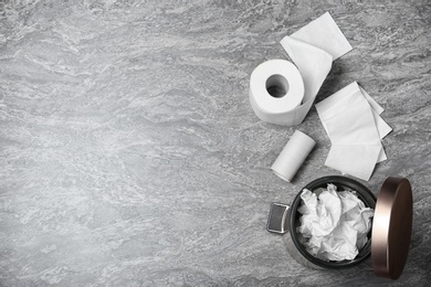 Photo of Trash bin with used toilet paper and new roll on grey background, top view. Space for text