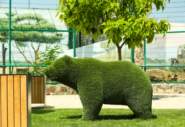 Beautiful bear shaped topiary at zoo on sunny day. Landscape gardening