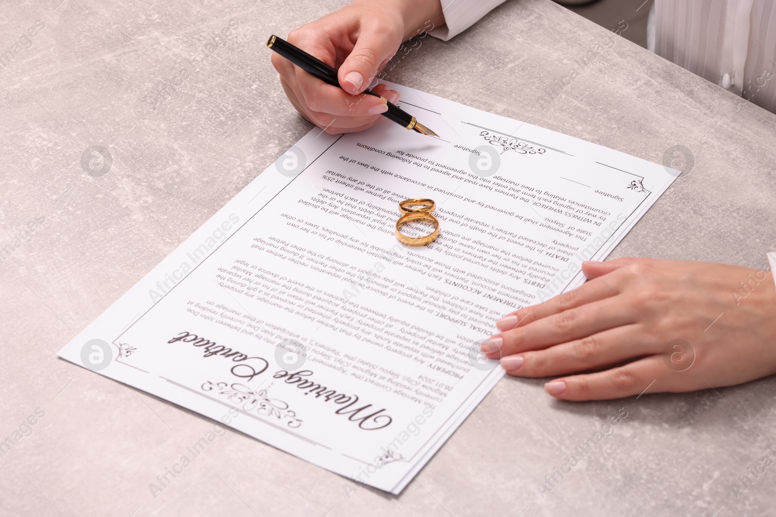 Photo of Woman signing marriage contract at light grey table, closeup