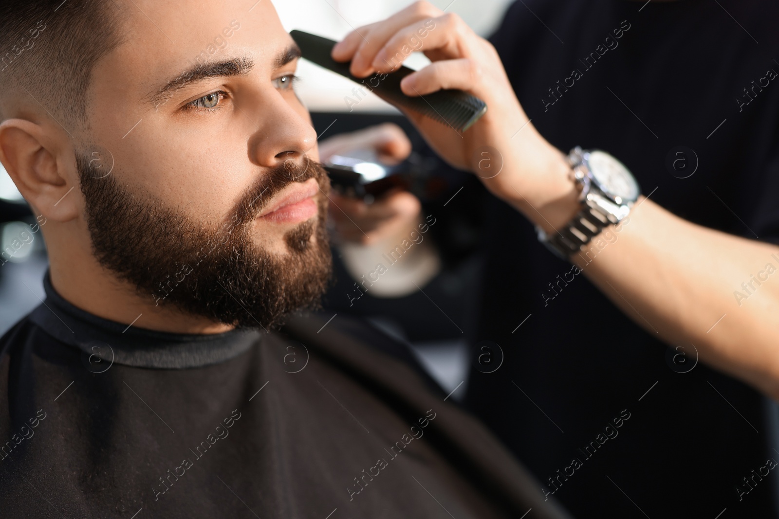 Photo of Professional hairdresser working with client in barbershop, closeup