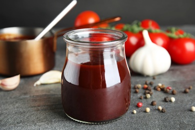 Composition with jar of barbecue sauce on grey table