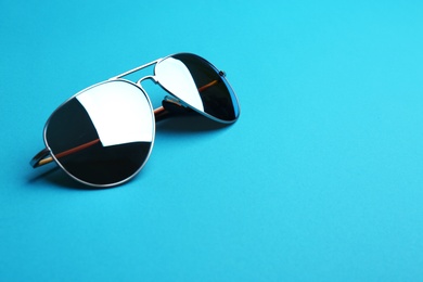 Stylish sunglasses on blue background, space for text. Fashionable accessory