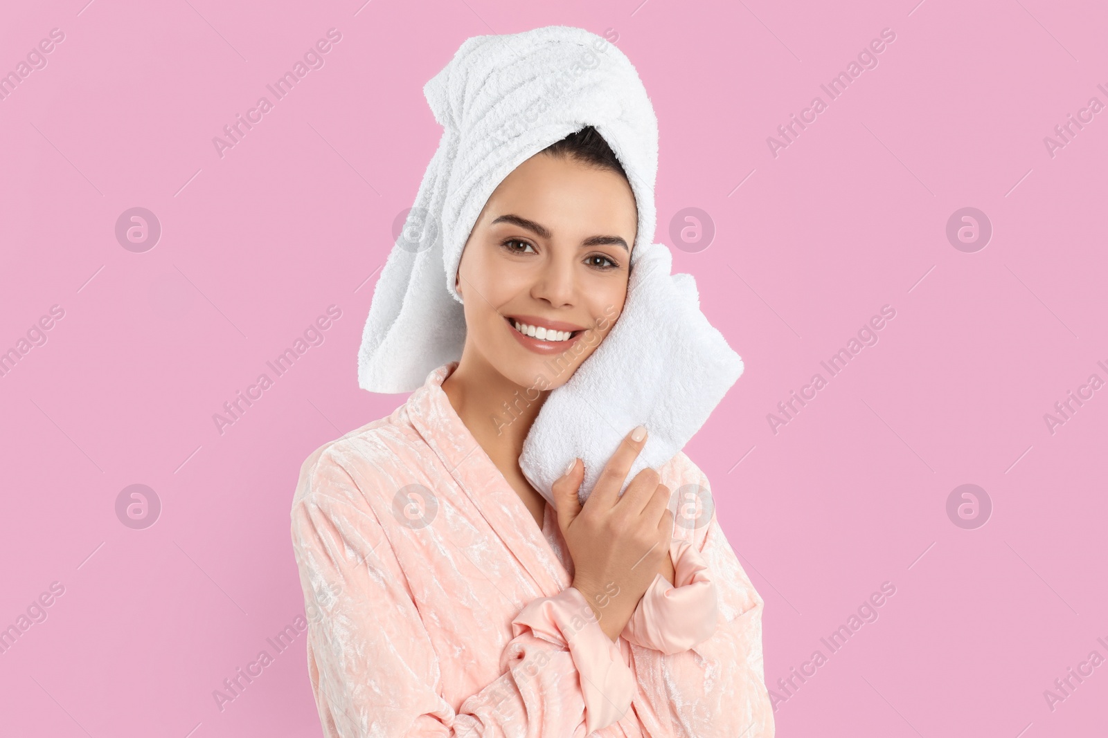 Photo of Young woman wiping face with towel on pink background