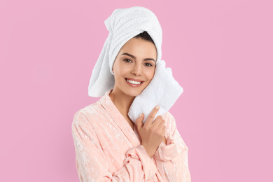 Photo of Young woman wiping face with towel on pink background