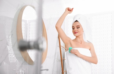 Photo of Beautiful young woman applying deodorant after shower in bathroom. Space for text