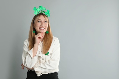 Happy woman in St Patrick's Day outfit on light grey background, space for text