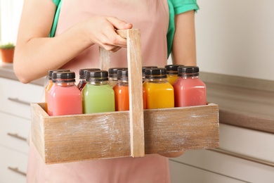 Woman holding basket with tasty juices indoors