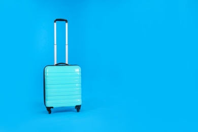 Photo of Travel suitcase on light blue background, space for text. Summer vacation