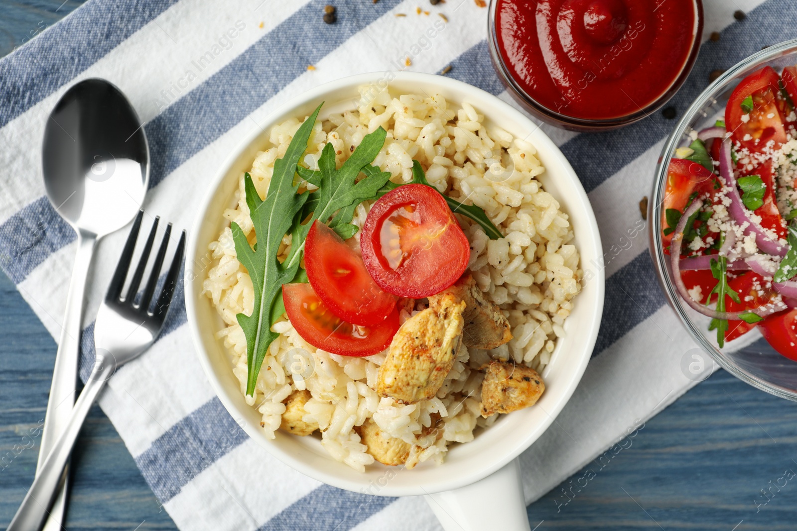 Photo of Delicious chicken risotto served on blue wooden table, flat lay