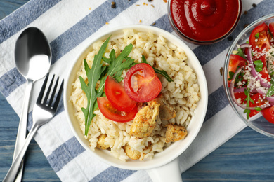 Photo of Delicious chicken risotto served on blue wooden table, flat lay