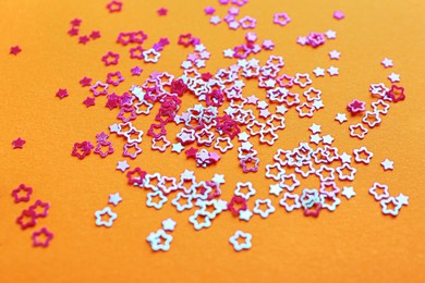 Photo of Shiny bright star shaped glitter on pale orange background