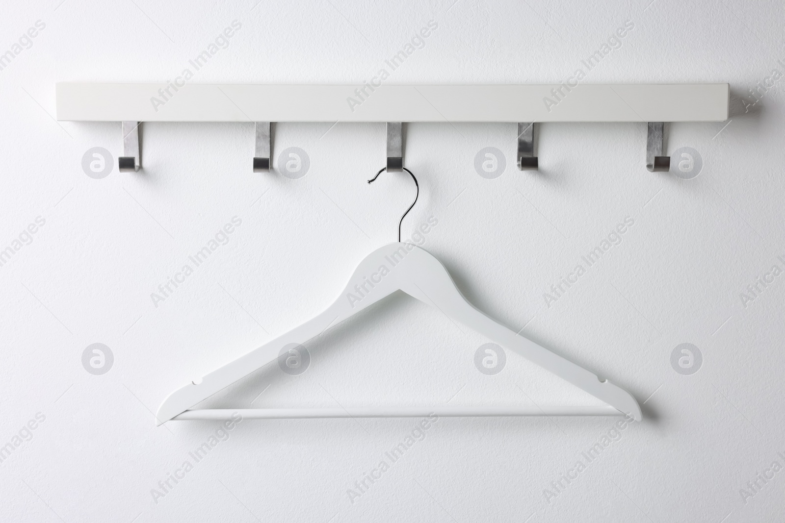 Photo of Rack with empty clothes hanger on white wall