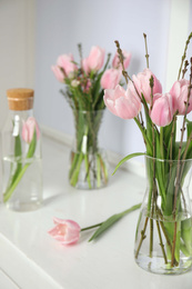 Photo of Beautiful bouquet with spring pink tulips on white window sill indoors
