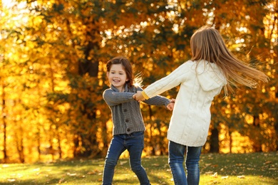 Happy little girls playing in sunny park. Autumn walk