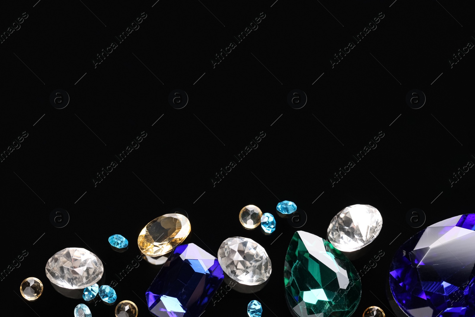 Photo of Different beautiful gemstones for jewelry on black background, flat lay. Space for text