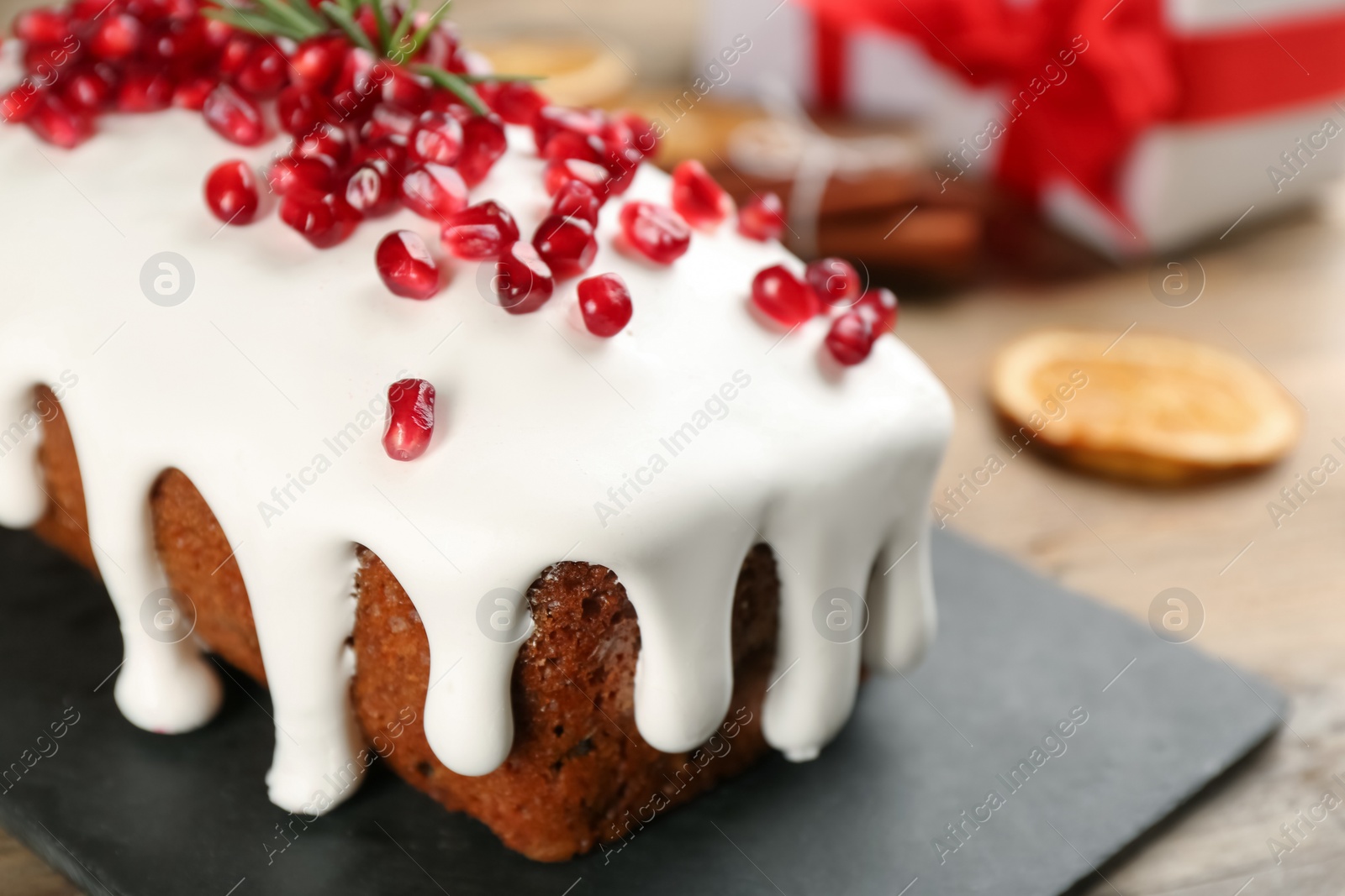 Photo of Traditional classic Christmas cake decorated with pomegranate seeds and rosemary on table, closeup