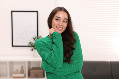 Photo of Beautiful young woman in stylish warm sweater at home