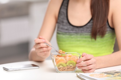 Photo of Young woman in fitness clothes having healthy breakfast at home, closeup