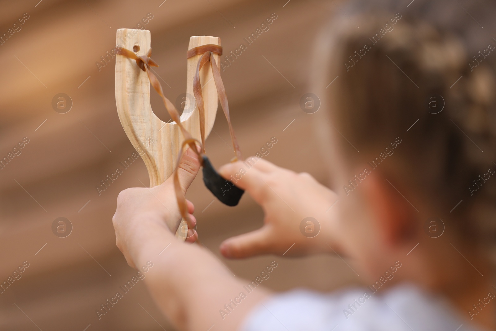 Photo of Little girl playing with slingshot outdoors, closeup