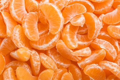 Fresh ripe tangerine pieces as background, top view