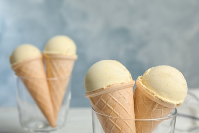 Delicious vanilla ice cream in waffle cones served on table, closeup