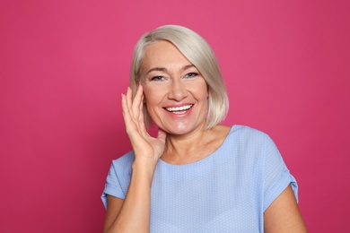 Photo of Portrait of mature woman laughing on color background