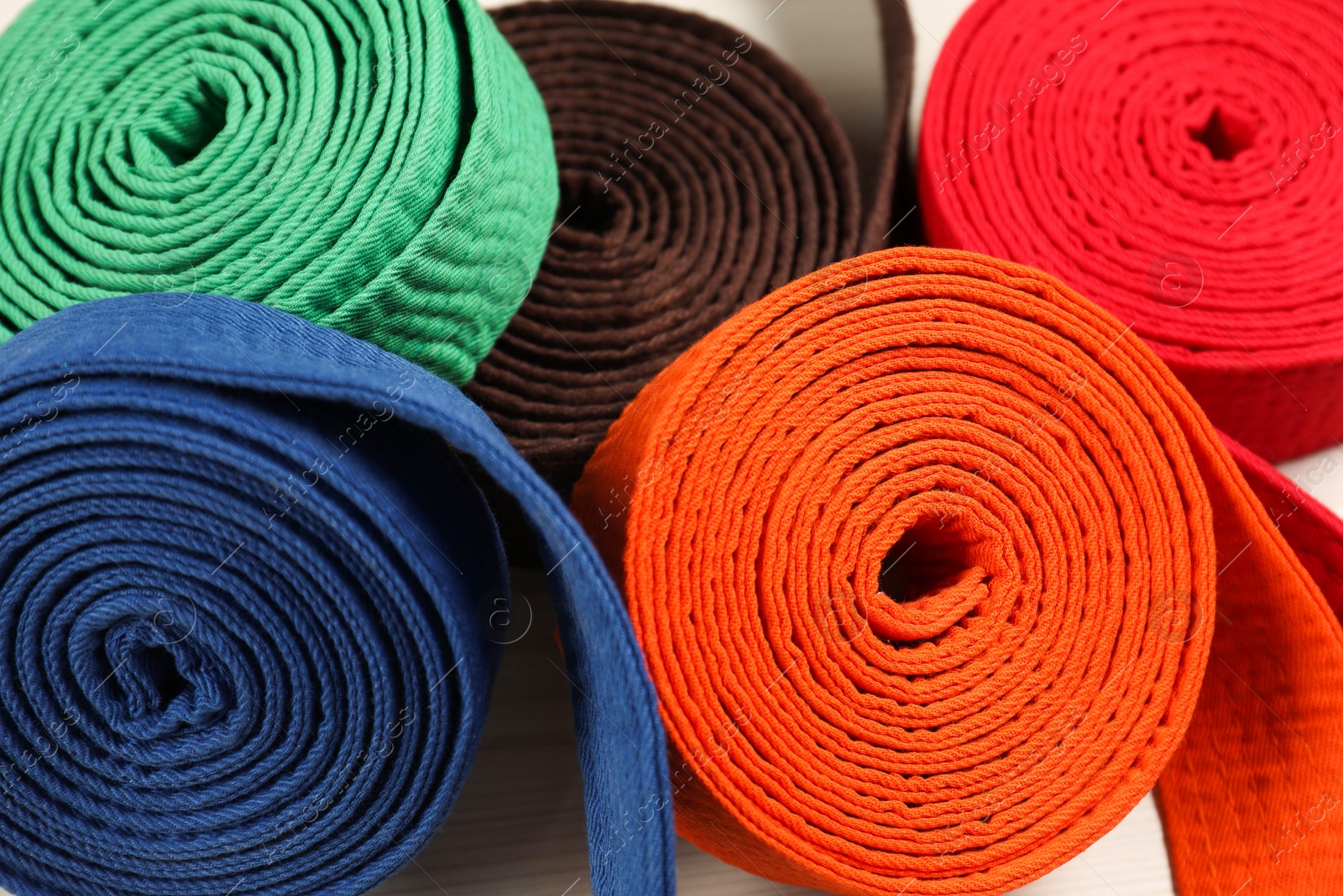 Photo of Colorful karate belts, closeup. Martial arts uniform