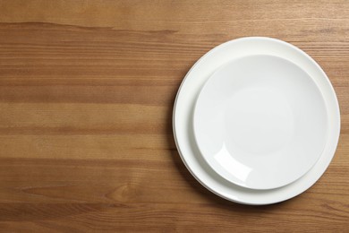 Empty ceramic plates on wooden table, top view. Space for text