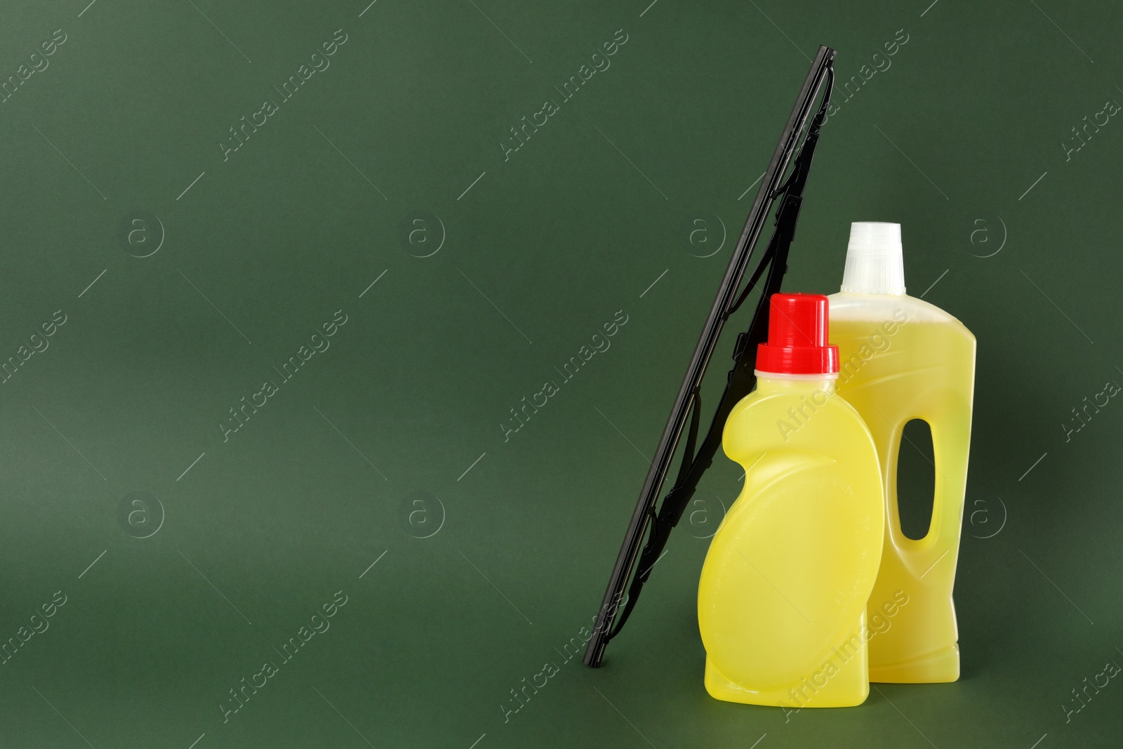 Photo of Bottles of windshield washer fluids and wiper on dark green background. Space for text