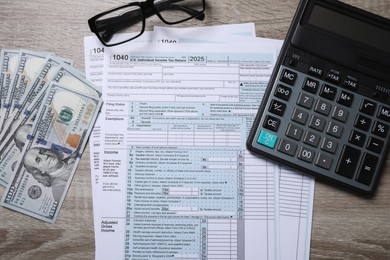 Payroll. Tax return forms, dollar banknotes, glasses and calculator on wooden table, flat lay
