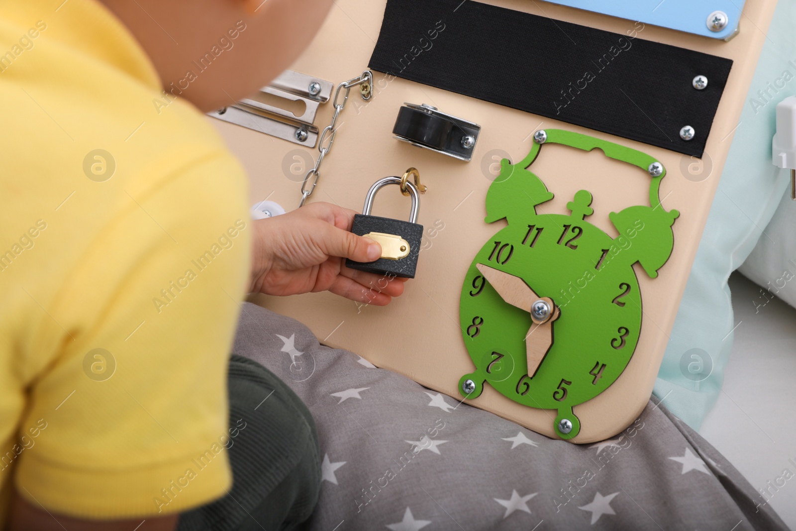 Photo of Little child playing with busy board on bed, closeup
