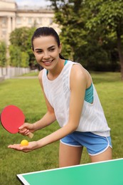 Young woman playing ping pong outdoors on summer day