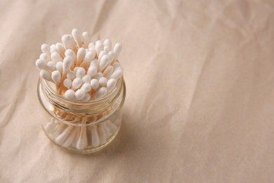 Jar of clean cotton buds on crumpled paper, closeup. Space for text