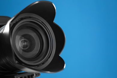 Photo of Professional video camera on blue background, closeup view of lens