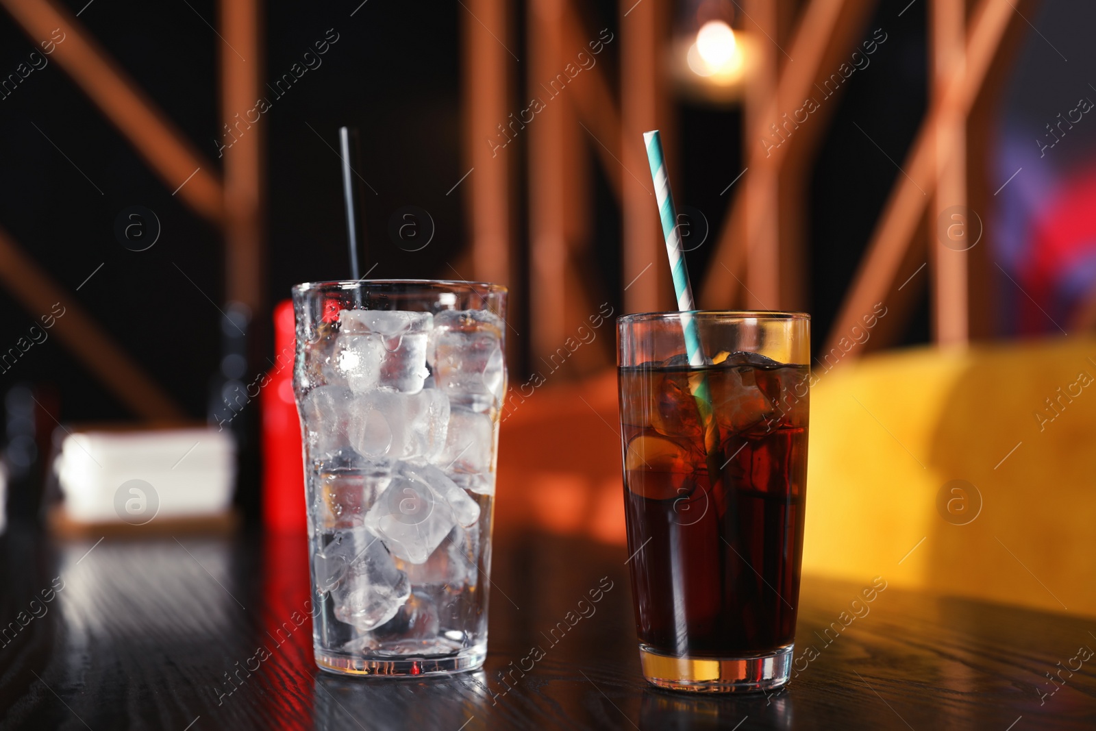 Photo of Glasses with refreshing cola and ice cubes on table indoors
