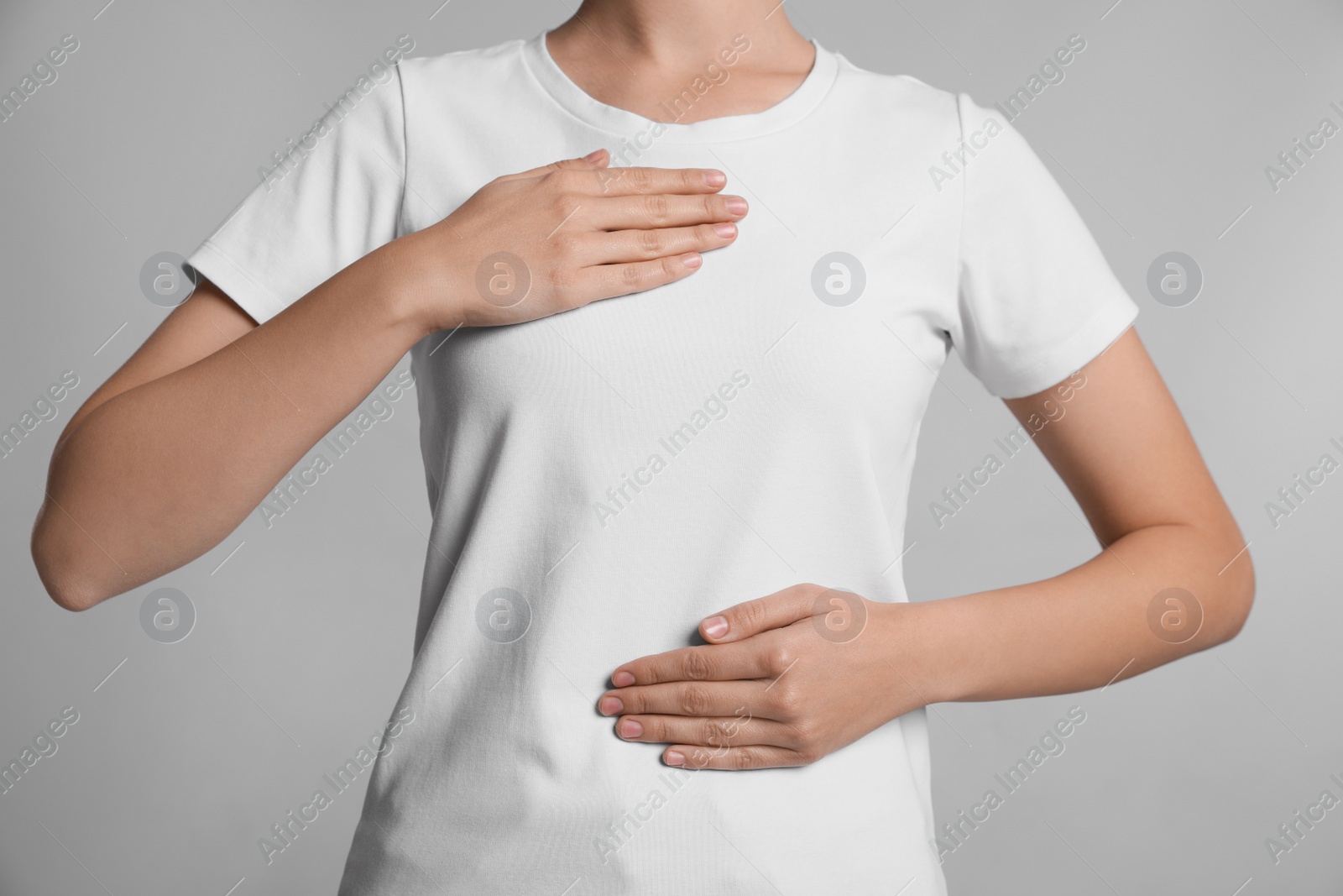 Photo of Woman holding hands near chest on light grey background, closeup