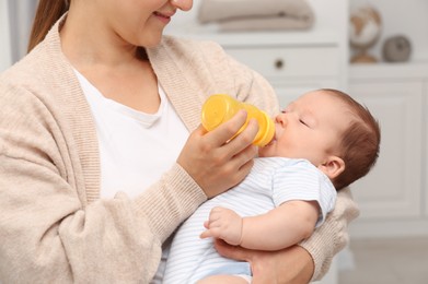 Photo of Mother feeding her cute child with infant formula indoors