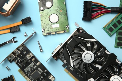 Photo of Graphics card and other computer hardware on light blue background, flat lay