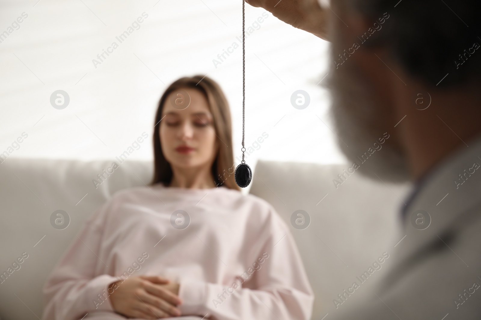 Photo of Psychotherapist using pendulum during hypnotherapy   session in office