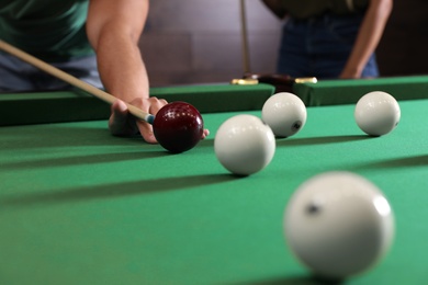 Young man and woman playing billiard indoors, closeup