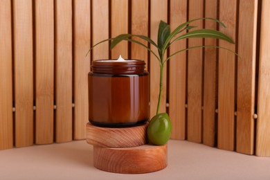 Photo of Jar of natural cream with olive essential oil on wooden background