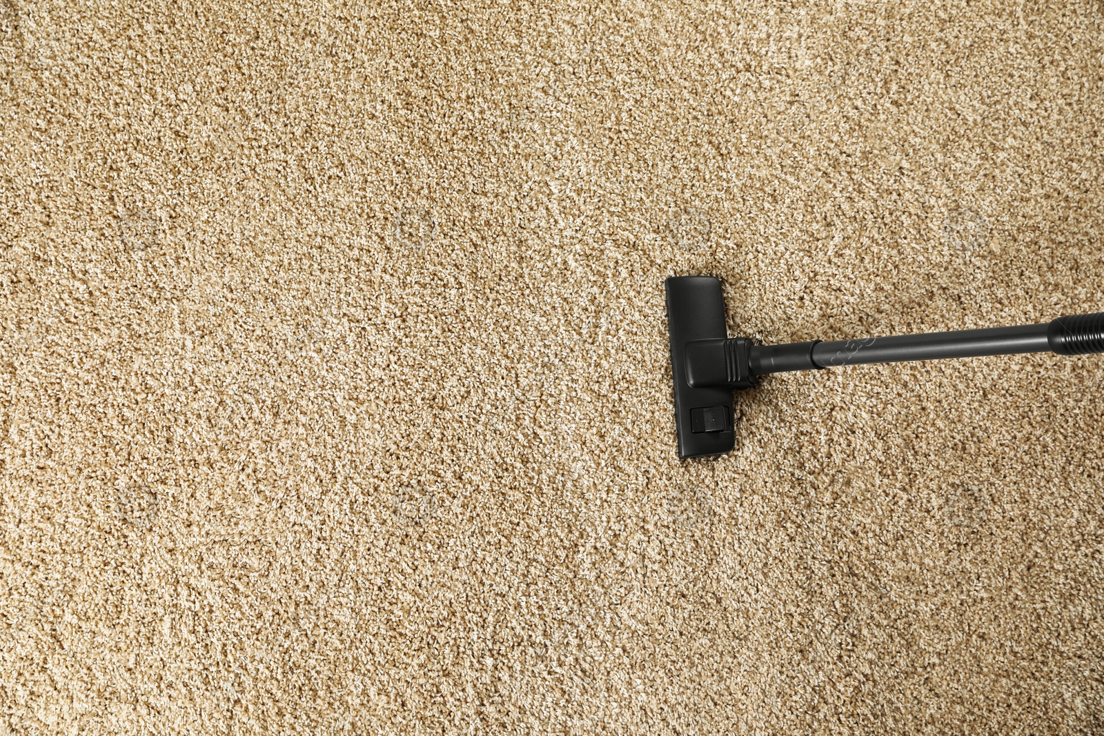 Photo of Removing dirt from beige carpet with modern vacuum cleaner, top view. Space for text