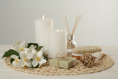Photo of Composition with beautiful jasmine flowers, soap and burning candles on white wooden table