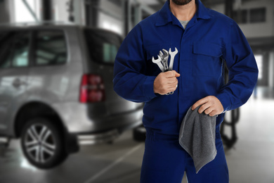 Image of Professional mechanic with wrenches and rag at tire shop, closeup