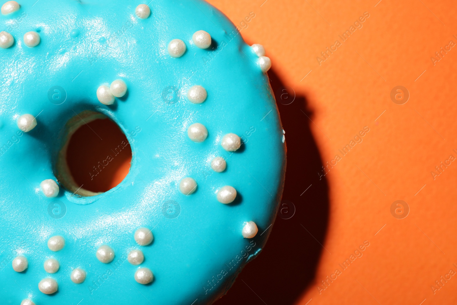 Photo of Delicious glazed doughnut on orange background, top view